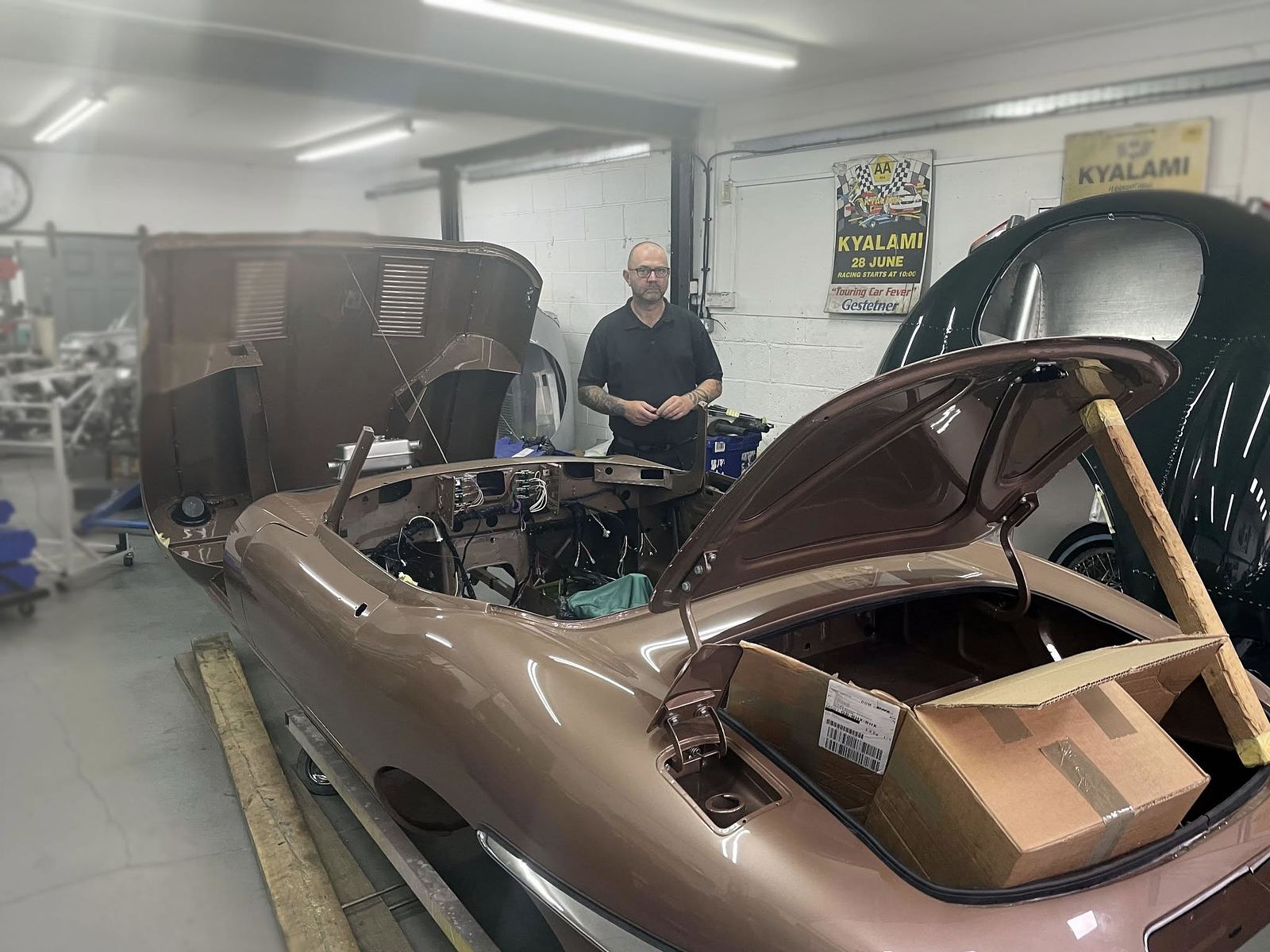 A classic car mid-restoration with bonnet and boot open
